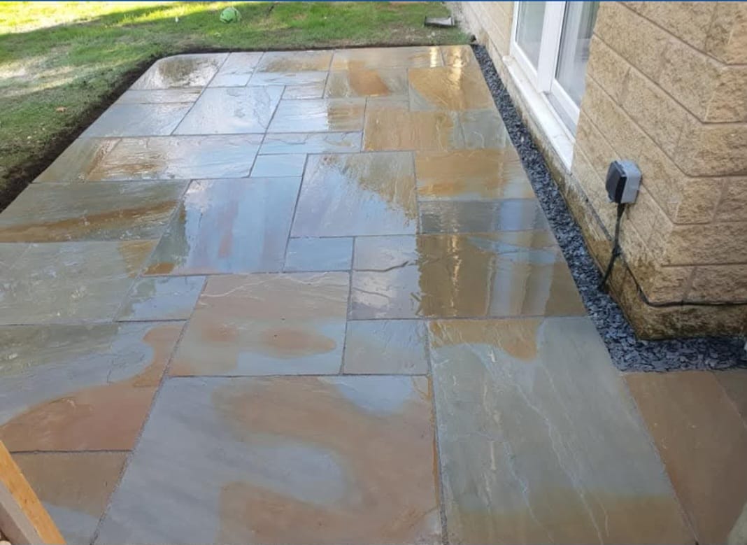 Natural stone paving beside a home and lawn